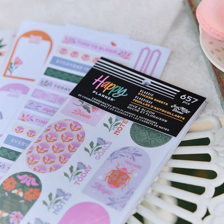 Close-up of Hive & Bloom sticker book and floral planning stickers beside pastel macarons