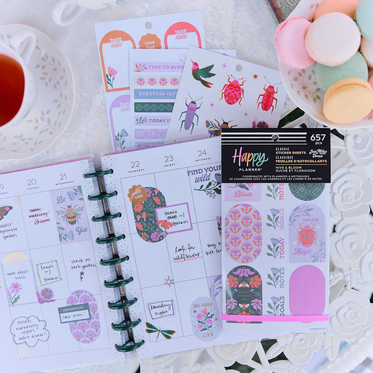 Happy Planner Hive & Bloom sticker book and garden stickers beside a weekly spread, tea and pastel macarons