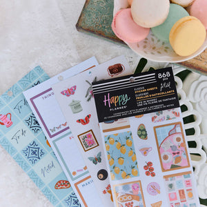 Happy Planner Life In Whimsy sticker book beside decorated planner pages and pastel macarons