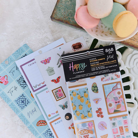 Happy Planner Life In Whimsy sticker book beside decorated planner pages and pastel macarons