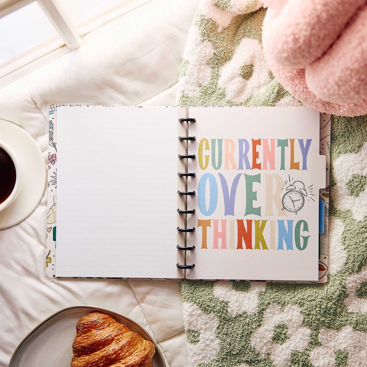 Open Pajama Plans notebook with Currently Overthinking artwork beside coffee and a croissant