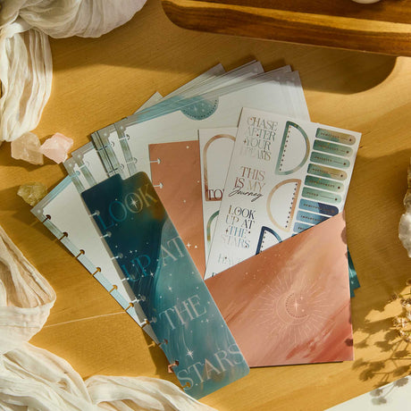 Starlit Glow celestial sticker sheets and starry inserts on a wooden surface