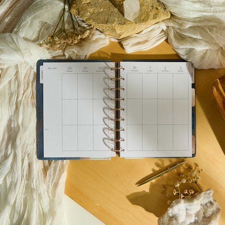 Starlit Glow planner blank weekly spread with metallic discs on a sunlit desk