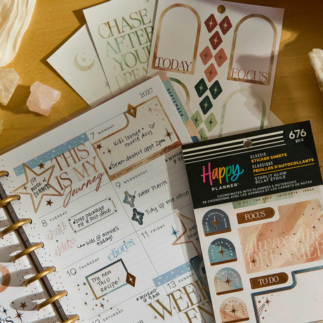 Starlit Glow celestial sticker sheets beside a decorated disc-bound planner