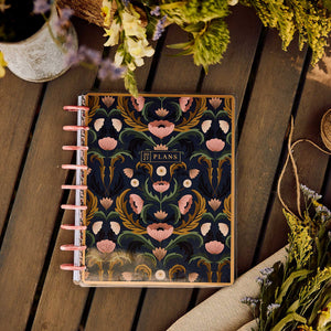 Happy Planner Twilight Tapestry Classic Horizontal Planner 2027: Ornate floral cover and pink discs on a wooden table