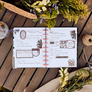 Happy Planner Twilight Tapestry Classic Horizontal Planner 2027: Open pages with handwritten notes and floral details on a wooden table