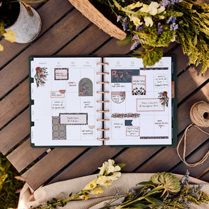 Twilight Tapestry planner open with floral stickers on a wooden table