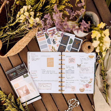 Wildflower Daydream Faith sticker book beside an open faith planner, flowers and a cross necklace