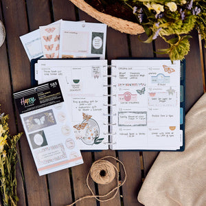 Happy Planner Wildflower Daydream sticker book beside a decorated weekly spread, flowers and twine