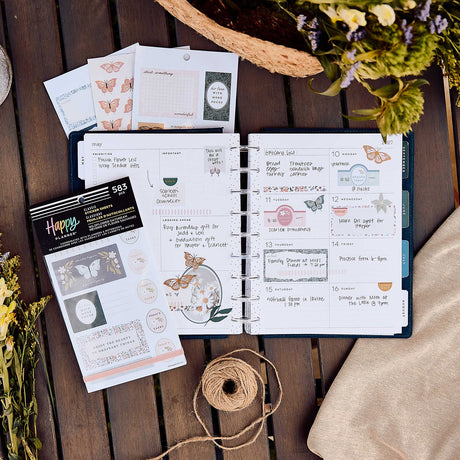 Happy Planner Wildflower Daydream sticker book beside a decorated weekly spread, flowers and twine