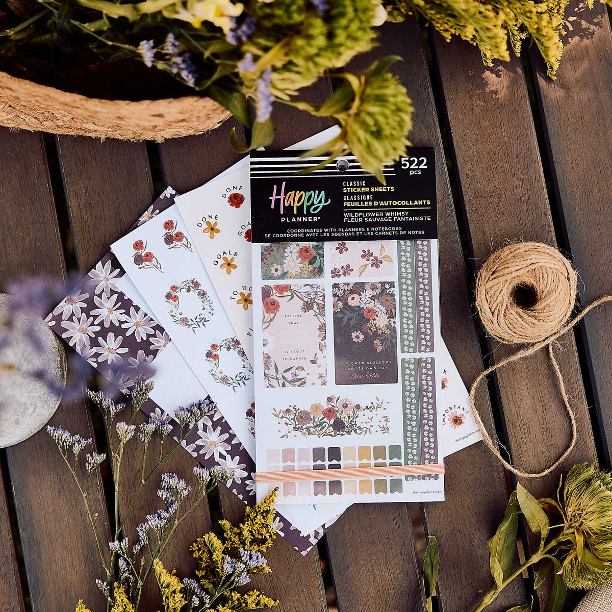 Wildflower Whimsy sticker book and floral sheets on a wooden table beside flowers and a spool of twine