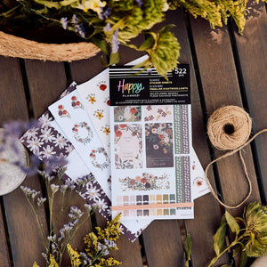 Wildflower Whimsy sticker book and floral sheets on a wooden table beside flowers and a spool of twine