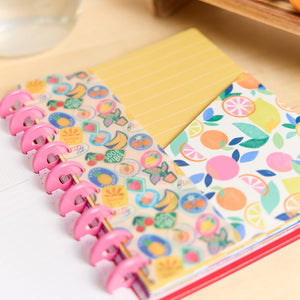 Notebook with colorful fruit-themed stickers on a wooden surface