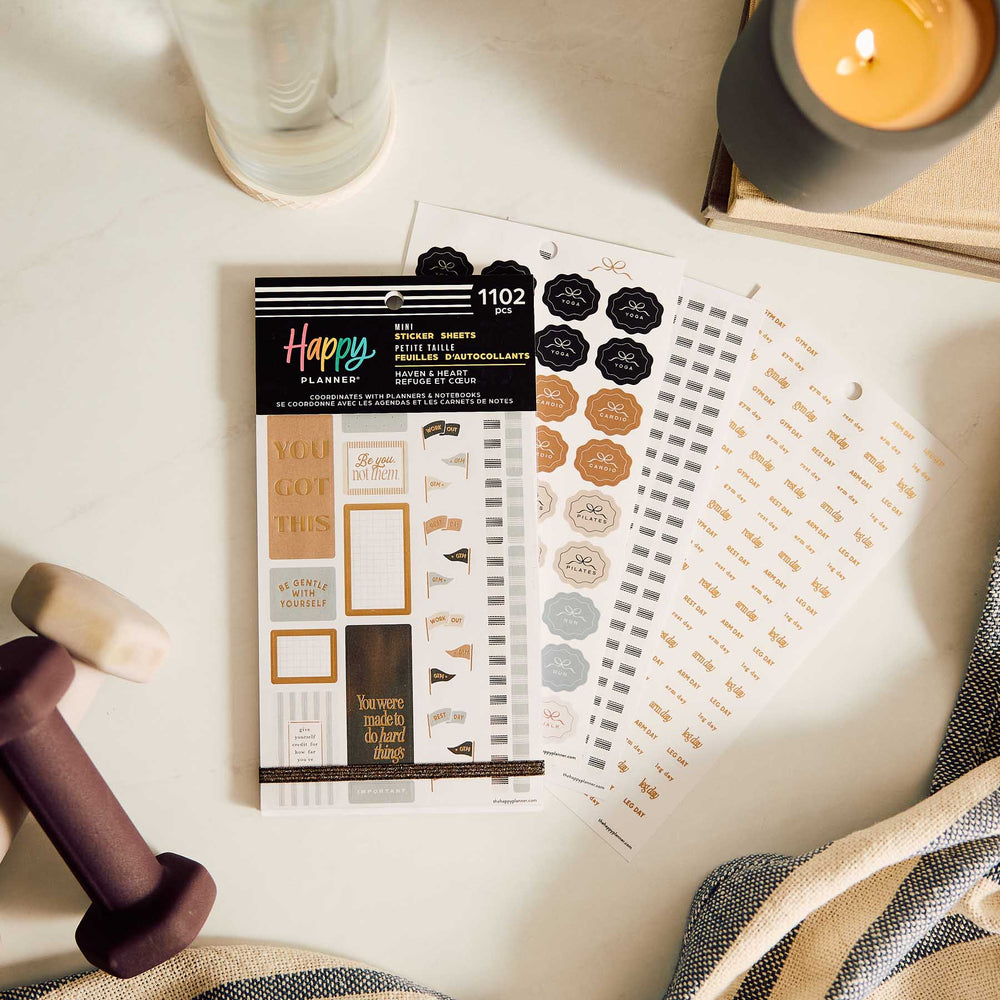 Fitness Mini sticker book and tracking sheets beside a candle, water bottle and dumbbell