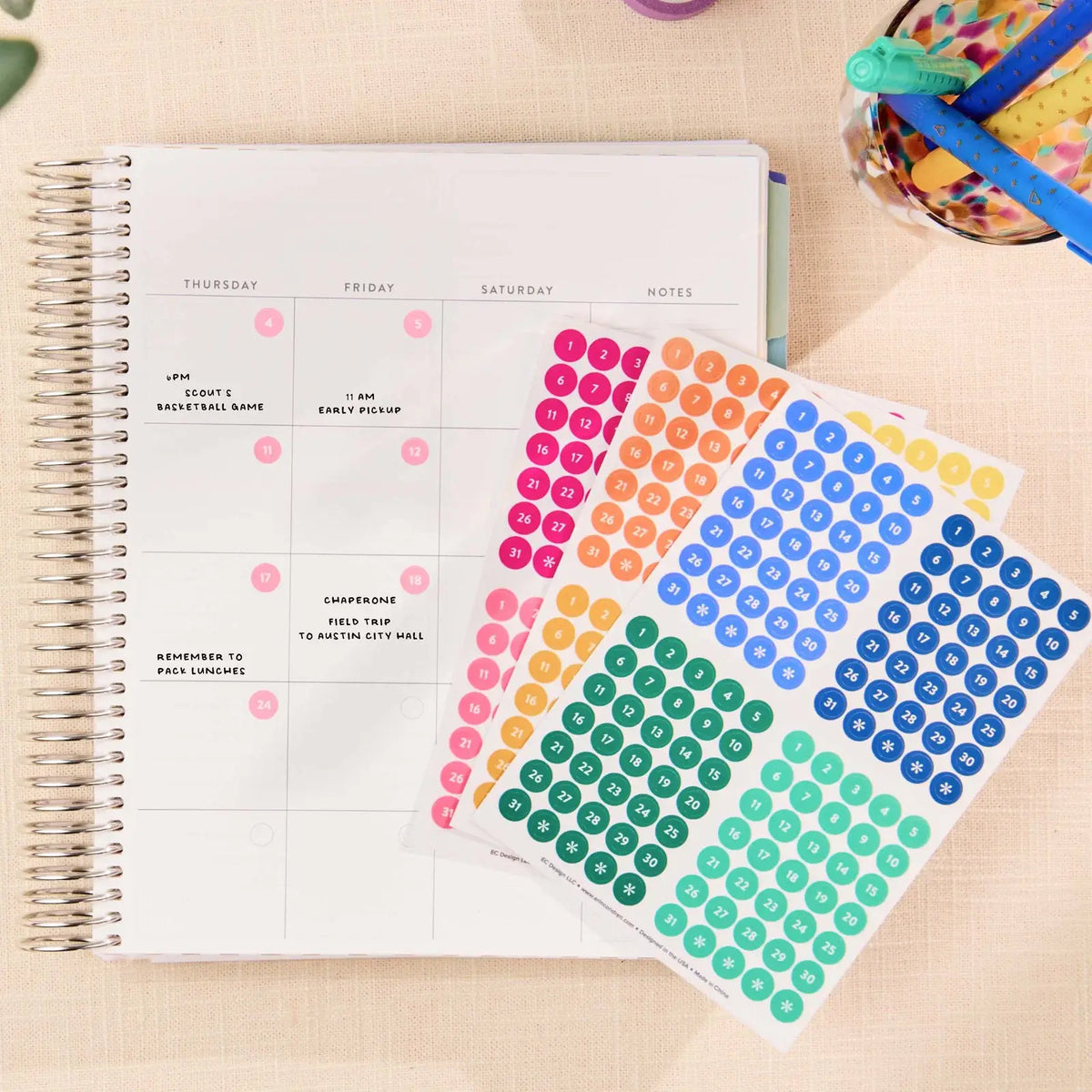 Erin Condren date dots: Date dot sticker sheets beside an open coiled planner
