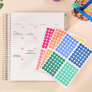 Erin Condren date dots: Date dot sticker sheets beside an open coiled planner