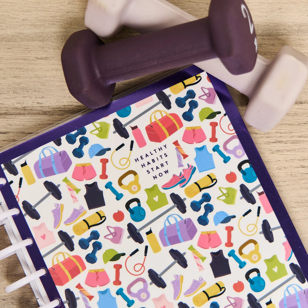 Happy Planner Classic Fitness Planner - 12 Month Dated 2026 planner with a purple dumbbell on a wooden surface