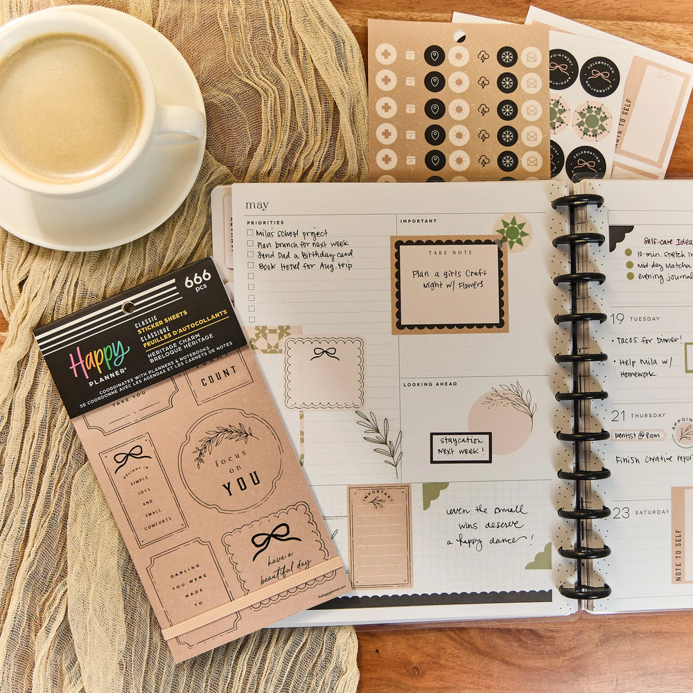 Happy Planner Heritage Charm Classic Sticker Book and a cup of coffee on a wooden surface