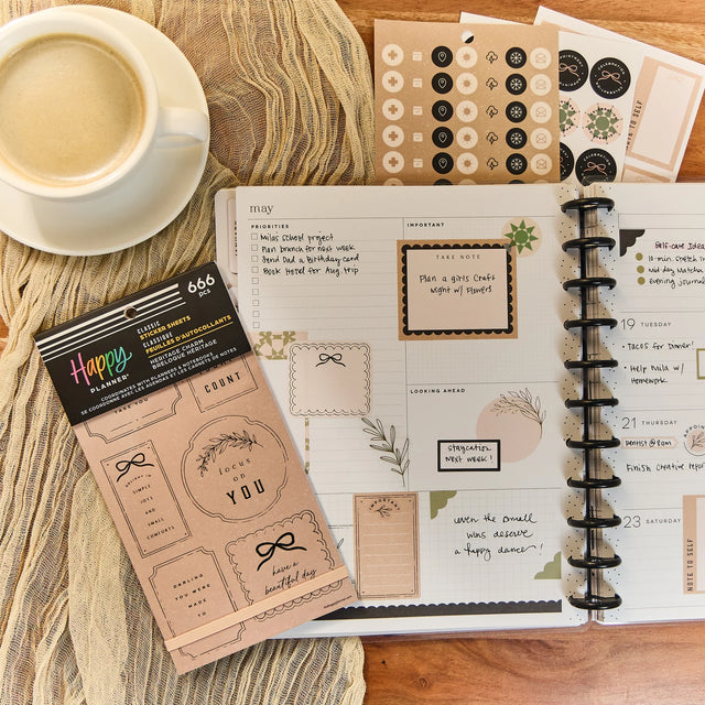 Happy Planner Heritage Charm Classic Sticker Book and a cup of coffee on a wooden surface