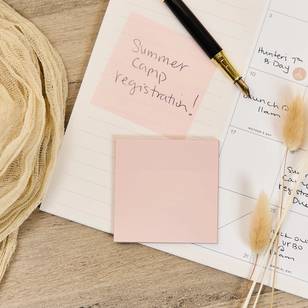 Notebook with Happy Planner Modern Charm Velum Sticky Notes, pen, and dried plants on a wooden surface