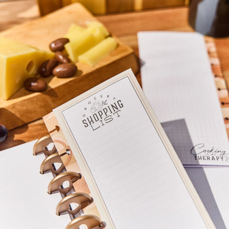 Notebook with Happy Planner Rustic Roots Grocery List Classic Folded Fill Paper on a table with cheese and nuts