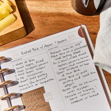 Recipe for Baked Brie with Apples and Pecans on a notebook with a wooden table background.
