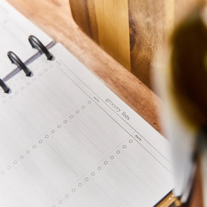 Meal planner with a blank page for grocery lists on a wooden surface