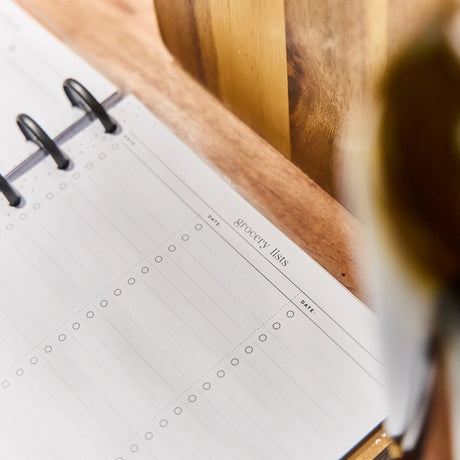 Meal planner with a blank page for grocery lists on a wooden surface