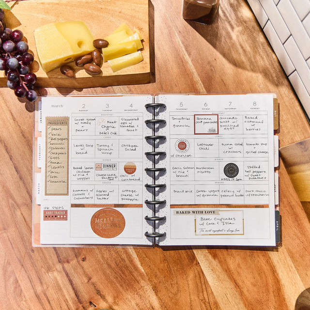 Happy Planner Classic Meal Planner on a wooden table with food items in the background