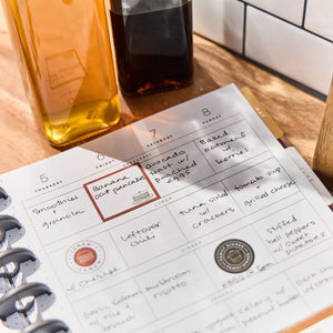 Daily planner with meal planning notes on a wooden table