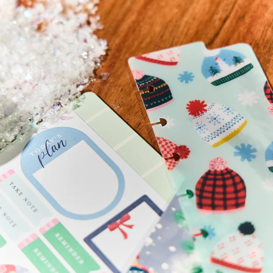 Decorative planner stickers with winter-themed designs on a wooden surface.