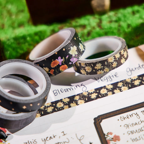 Three rolls of floral-patterned tape on a surface with greenery in the background