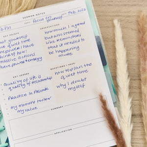 Notebook with sermon notes on a wooden surface with dried plants