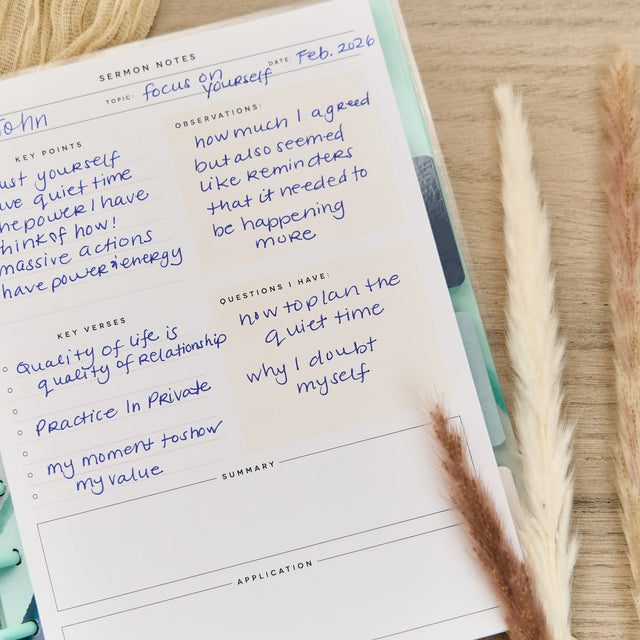 Notebook with sermon notes on a wooden surface with dried plants
