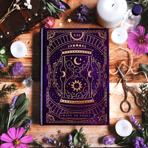 Decorative book titled 'Made of Stars' journal Surrounded by candles, crystals, and flowers on a wooden surface.