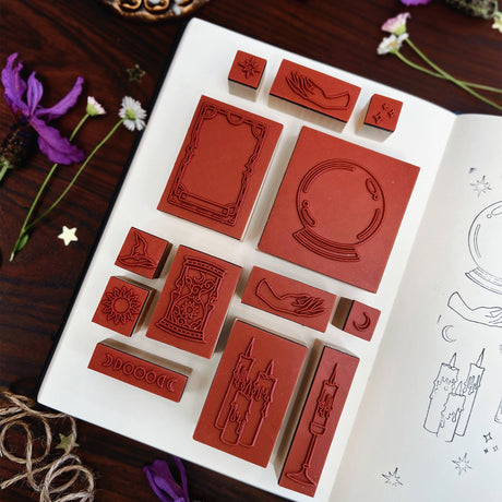Practical Magic Stamp Set of red rubber stamps on a wooden surface with flowers and a book.