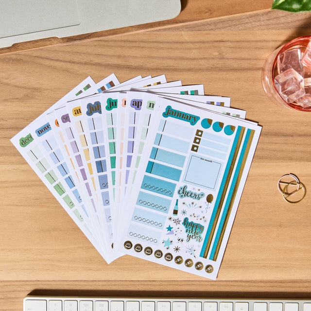 Set of planner stickers on a wooden surface with a keyboard in the foreground