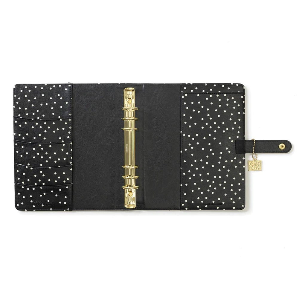 Black planner with gold binding and white polka dot pattern on a white background
