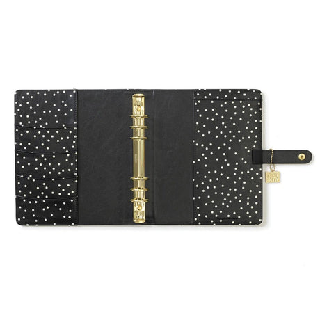 Black planner with gold binding and white polka dot pattern on a white background