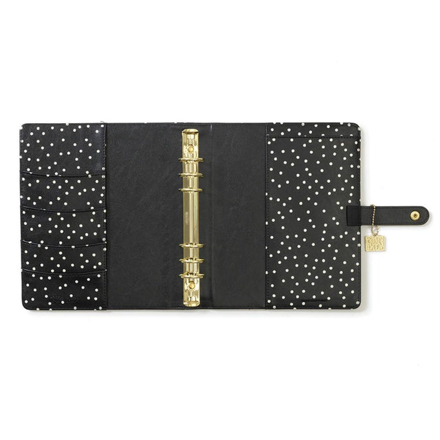 Black planner with gold binding and white polka dot pattern on a white background