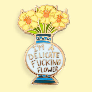 I'm A Delicate Fucking Flower Lapel Pin gold-colored enamel lapel pin featuring a stylized flower vase with flowers and the text 'I'm A Delicate Fucking Flower'.