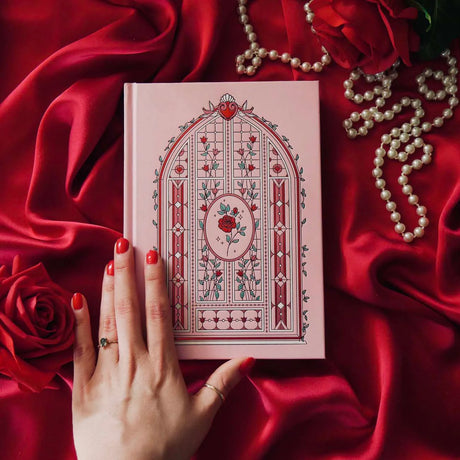 Lust & Longing A5 Journal with intricate design on a red fabric background with a hand and pearls.